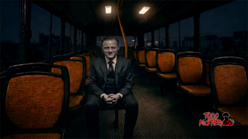 Hombre de traje, pálido y sonriendo, sentado en un colectivo. Imagen ilustrativa del pasajero fantasma